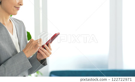 Female business person using a smartphone in the office 122722971
