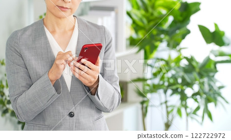 Female business person using a smartphone in the office 122722972