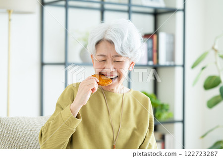 Senior woman eating rice crackers 122723287