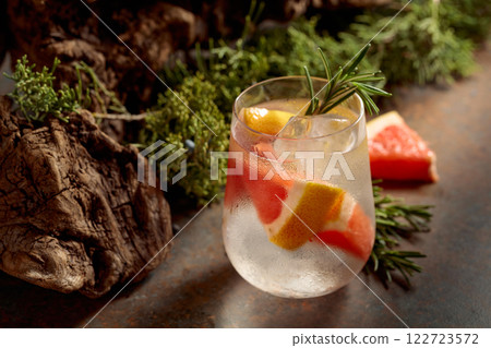 Cocktail: gin and tonic with ice, grapefruit, and rosemary on a rustic background. Cocktail: gin and tonic with ice, grapefruit, and rosemary on a rustic background. 122723572