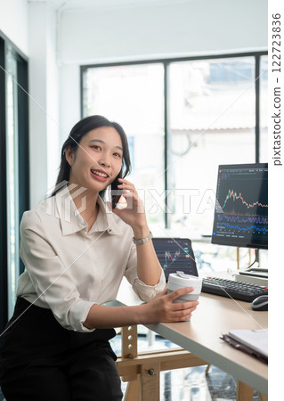 Woman examines stock graphs and talks on phone 122723836