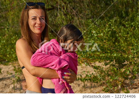 Mother dries her child with a towel after swimming in the river Mother dries her child with a towel after swimming in the river 122724406