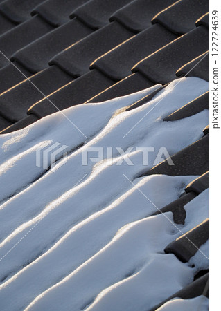 The snow that has accumulated on the Japanese tile roofs begins to melt. 122724639