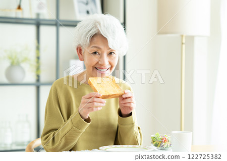 Senior woman eating bread for breakfast 122725382