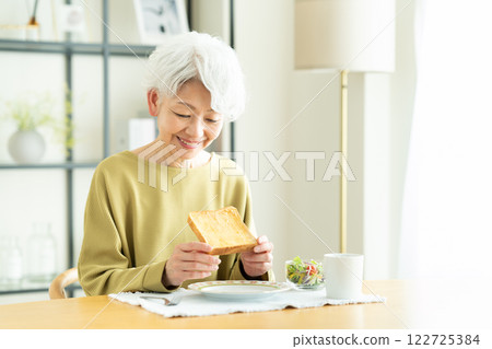 Senior woman eating bread for breakfast 122725384