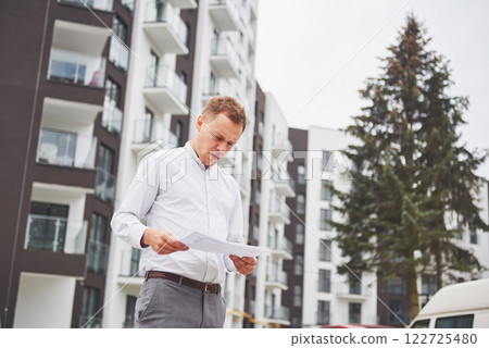 business, building, industry, technology and people concept - smiling builder in hardhat with tablet pc computer over group of builders at construction site 122725480