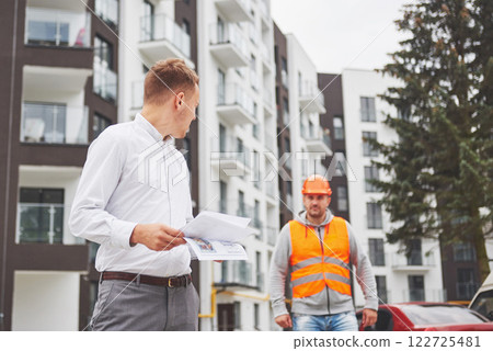 business, building, teamwork and people concept - group of smiling builders in hardhats at construction site 122725481