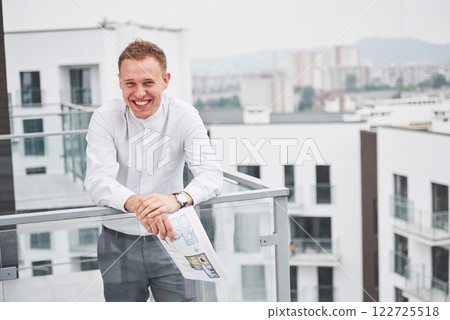 Smiling young architect or engineering builder in hard hat with tablet over group of builders at construction site, architect watching some a construction, business, building, industry, people concept 122725518