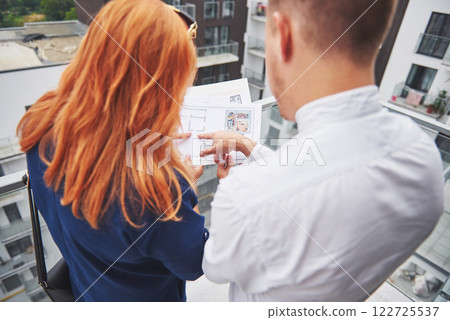 An engineer showing blueprint to her client An engineer showing blueprint to her client 122725537