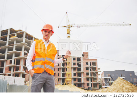 architecture and home renovation concept - man in helmet and gloves with blueprint in factory architecture and home renovation concept - man in helmet and gloves with blueprint in factory 122725556