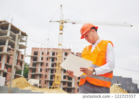architecture and home renovation concept - man in helmet and gloves with blueprint in factory architecture and home renovation concept - man in helmet and gloves with blueprint in factory 122725557