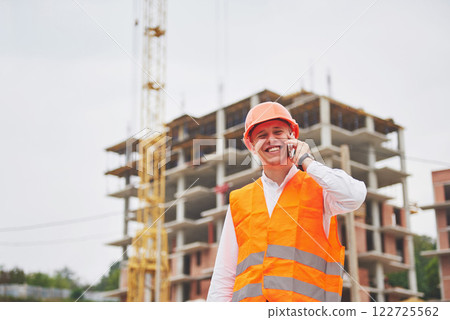 Young architect wearing a protective helmet standing on the mountains building outdoor background Young architect wearing a protective helmet standing on the mountains building outdoor background 122725562