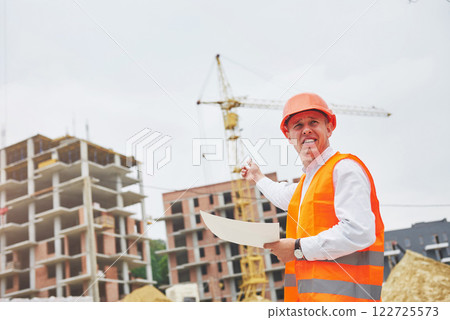 architecture and home renovation concept - man in helmet and gloves with blueprint in factory architecture and home renovation concept - man in helmet and gloves with blueprint in factory 122725573