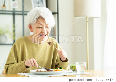 senior woman eating steak 122725612