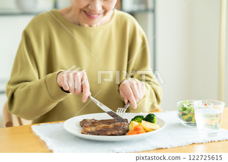 senior woman eating steak 122725615