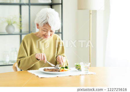 senior woman eating steak 122725616