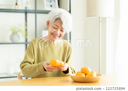 Senior woman eating mandarin oranges Senior woman eating mandarin oranges 122725894
