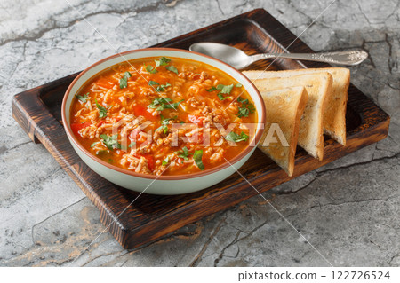 Comfort food Stuffed pepper soup is filled with a savory blend of ground beef, sausage, colorful bell peppers, tomatoes, and rice simmered in rich broth closeup in the bowl. Horizontal 122726524