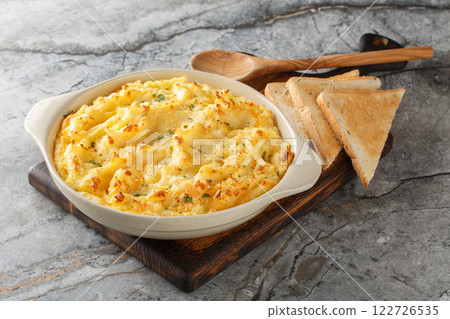Golden baked mashed potatoes with cheddar and parmesan cheese, cream, butter and herbs close-up in a baking dish. Horizontal 122726535