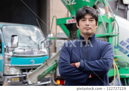 A man standing in front of a mixer truck A man standing in front of a mixer truck 122727229