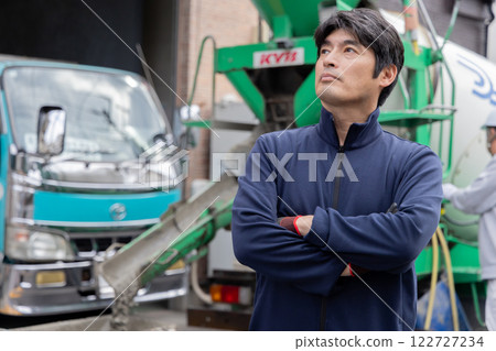 A man standing in front of a mixer truck 122727234