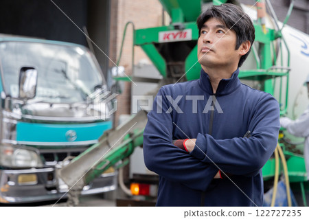 A man standing in front of a mixer truck 122727235