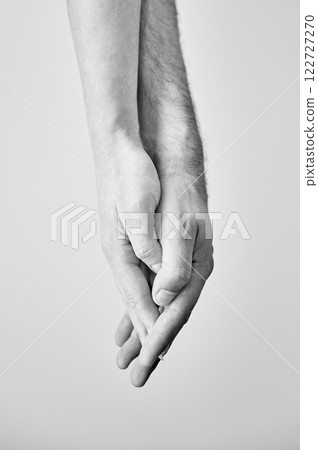 Close up view of hands of sweet couple. Young man and woman holding hands on light neutral background. Concept of love, intimacy, support, and trust. Black and white image. 122727270