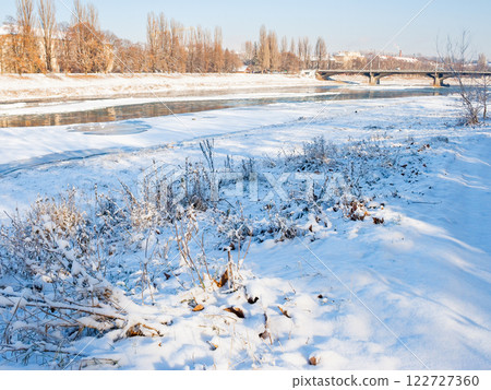 uzhhorod, ukraine - 03 jan, 2009: transportation bridge on the river uzh in winter. beautiful view on a sunny weather. urban landscape of the old city downtown. connection infrastructure 122727360