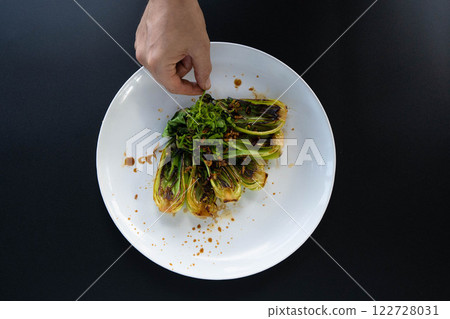 Hand picks vibrant bok choy from a white plate, showcasing fresh ingredients for Asian dishes. Hand picks vibrant bok choy from a white plate, showcasing fresh ingredients for Asian dishes. 122728031