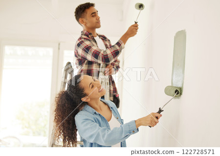 Painting, love and renovation with a couple doing DIY in a room for improvement and remodel of their home. Young man and woman working with green paint on a wall to renovate their domestic house 122728571