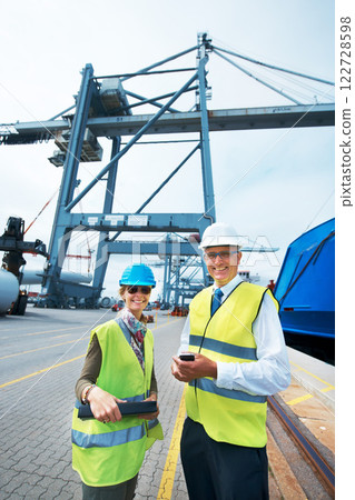 Industry workers working on a shipping dock to export stock packages, boxes or containers. Portrait of industrial, business and shipment employees at a cargo logistics outdoor warehouse with a crane. Industry workers working on a shipping dock to export stock packages, boxes or containers. Portrait of industrial, business and shipment employees at a cargo logistics outdoor warehouse with a crane. 122728598