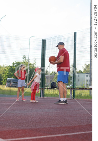 The father scolds the child for educational purposes. Naughty girl argues with her father during basketball break 122728704