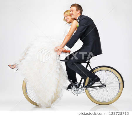 Happy, wedding and couple on a bicycle against a white background, after getting married together. Love, young bride and groom in dress and suit, cycling on a bike in marriage happiness or bliss Happy, wedding and couple on a bicycle against a white background, after getting married together. Love, young bride and groom in dress and suit, cycling on a bike in marriage happiness or bliss 122728713