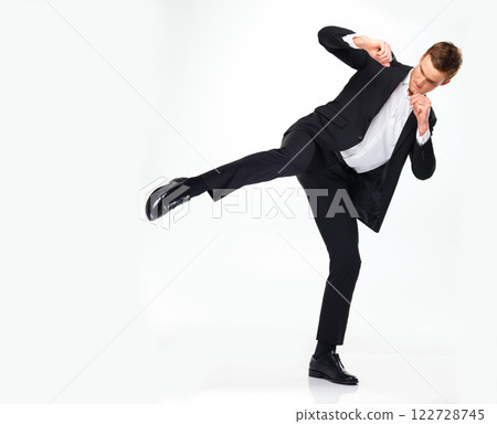 Business man doing a karate kick to the side while standing in a studio with copy space. Man in suit working on his fitness with martial arts training. Professional spy agent practicing to fight. 122728745