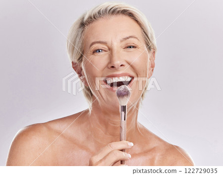 Beauty, makeup skincare with a senior model holding a blusher brush in studio against a gray background. Portrait of an elderly woman with a smile posing for wellness, healthcare and cosmetics 122729035