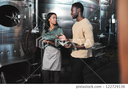 Wine production workers using alcohol machine or distillery equipment in warehouse winery. Business sommelier expert woman and man talking and working on quality control maintenance with a checklist 122729136