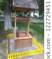 Wooden well with yellow fence in park.  122729451