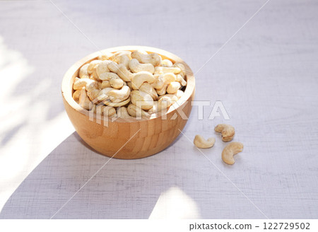 Cashew nuts in wooden bowl on white table with sunshine. Healthy food. Cashew nuts in wooden bowl on white table with sunshine. Healthy food. 122729502