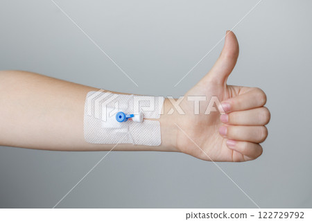 Hand with Peripheral venous catheter holding thumb up on grey background 122729792