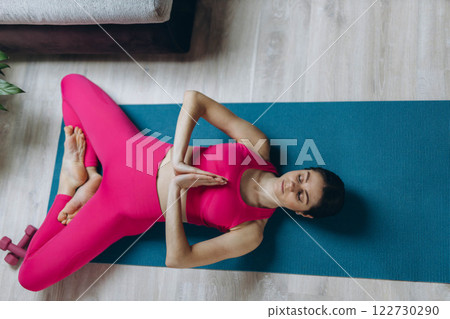A woman practicing yoga and meditation in lotus,Namaste pose at home, sitting on the floor 122730290