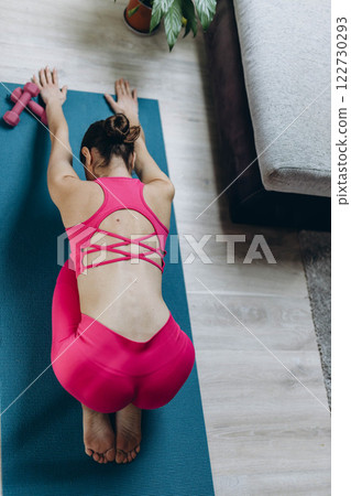 woman in a pink sports outfit practicing yoga,stretching at home, top view 122730293