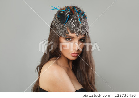 Pretty healthy woman with makeup, long brown curly hair and hair deco feathers accessories Pretty healthy woman with makeup, long brown curly hair and hair deco feathers accessories 122730456