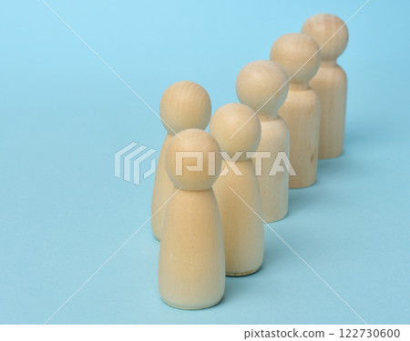 A row of wooden figures and one out of order on a blue background, concept of uniqueness A row of wooden figures and one out of order on a blue background, concept of uniqueness 122730600