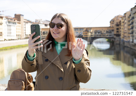 Beautiful 30s woman taking selfie on famous Old bridge in Florence. Traveling Europe in summer. Attractive female is exploring city. Top tourist attraction 122731547