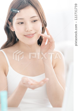 A woman in her twenties putting on makeup in the living room A woman in her twenties putting on makeup in the living room 122731739