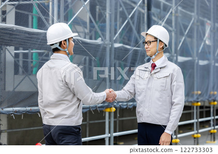 Workers working at a construction site shaking hands 122733303