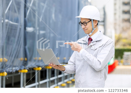 Man in work clothes holding a laptop Man in work clothes holding a laptop 122733346