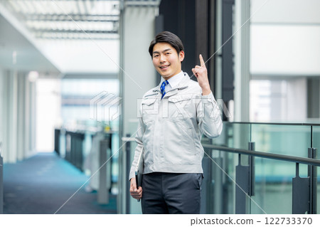 一名身著工作服的男子站在辦公室走廊裡 122733370