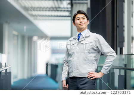 A man in work clothes standing in an office corridor A man in work clothes standing in an office corridor 122733371