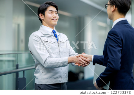 Handshake: A man in work clothes and a man in a suit 122733378